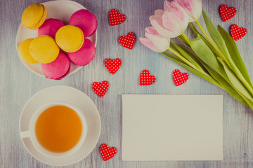 cup of tea, and a bouquet of tulips, Macaron cakes - view from above with copy space - a concept congratulations on Valentine's Day