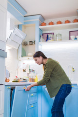 Side view of the young woman who standing in the kitchen and opening the kitchen curbstone