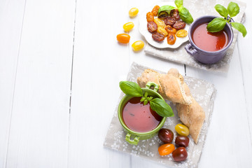 soup gospacho in bright cups with basil on a white background