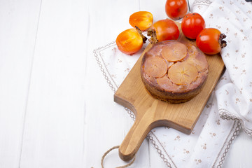 pie with persimmon on a brown wooden board on a white background and a white tablecloth