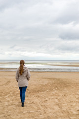Woman on the beach looks on the sea waves