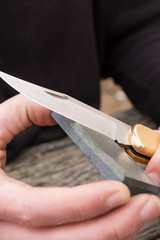 male hands sharpening pin knife.