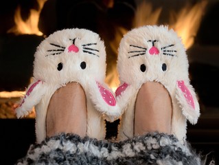 pair of bunny slippers by fireplace with striped afghan