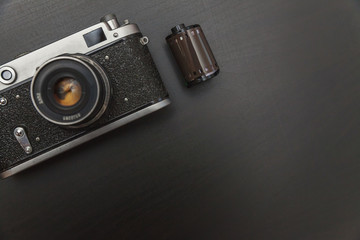 Vintage Film Camera And Roll On Black Wooden Background Technology Development Photographer Concept with copy space. Top View