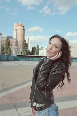 Fototapeta premium Sexy beautiful girl in leather jacket poses in a city center