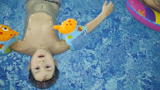 Children's water games in the pool. Little kids bathe in the swimming pool