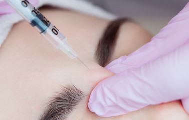The doctor cosmetologist makes the Botulinum Toxin injection procedure for tightening and smoothing...