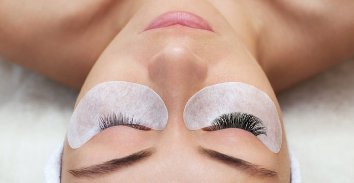 Eyelash removal procedure close up. Beautiful Woman with long lashes in a beauty salon. Eyelash extension.