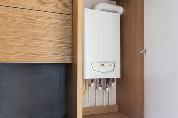 Opened kitchen cabinet and a gas boiler, a smart solution to hide the boiler inside furniture....