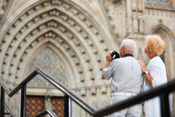 Obraz na płótnie Canvas Back view of senior couple travellers making photo with camera