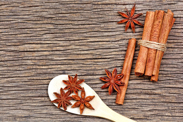 Anise star in a wooden spoon with cinnamon sticks on table