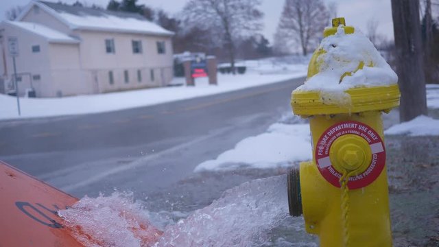 Close up of fire hydrant spraying water out onto road in winter