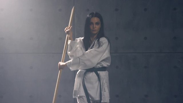 Young woman in kimono practicing martial arts with jodo
