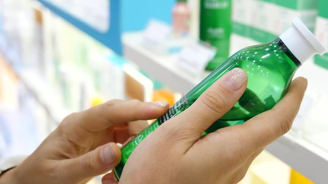 Woman Reading Label On Cosmetics Bottle In Beauty Care Shop. Closeup. 4K. 