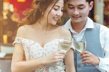 Asian man are holding glass of wine and cheer with his girlfriend in restaurant.