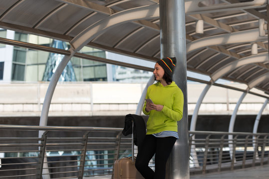 Happy traveler using a smartphone in city building while is waiting for transport