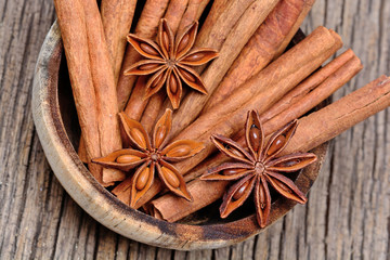 Bowl with cinnamon sticks and anise star on rustic table