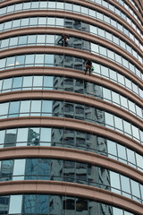 Fototapeta premium A pair of window washers overlaps with the reflection of a building across the street