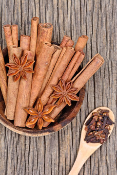Cinnamon sticks with anise star in a bowl and cloves on rustic table