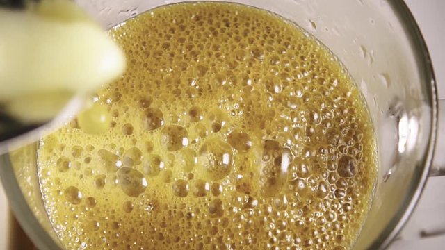 Fresh squeezed apple juice is poured into a glass in slow motion