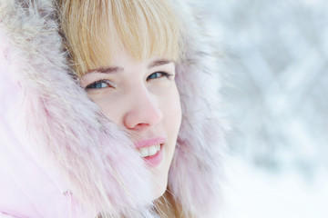 Close up portrait of a beautiful blonde young woman in a winter park