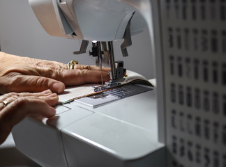 Hands holding fabric while operating a sewing machine - selective focus and motion