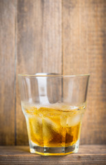 Glass with whiskey on the rustic wooden background. Selective focus. Shallow depth of field.