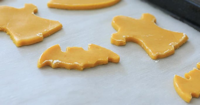Woman's hands making cookies from raw dough in the form of halloween symbols