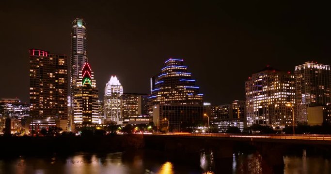 A night timelapse view of the Austin city skyline with the Colorado River in the foreground.  	