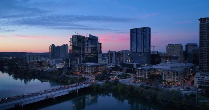 A slow push forward aerial establishing shot of the Austin, Texas skyline on an early Winter evening as traffic passes over the South 1st Street Bridge.  	