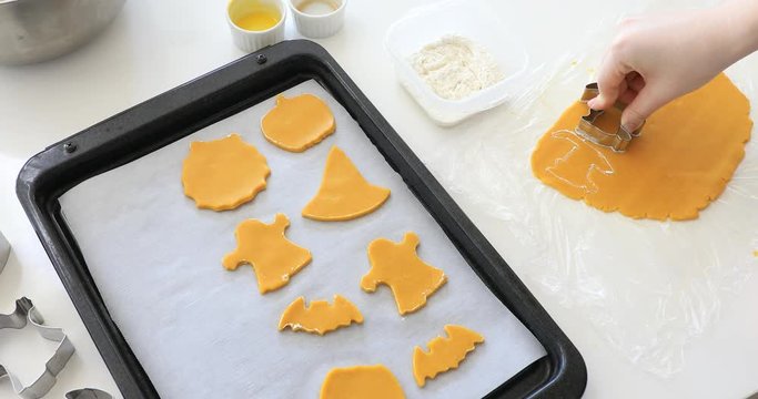 Woman's hands making cookies from raw dough in the form of halloween symbols