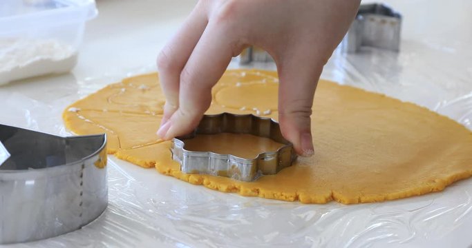 Woman's hands making cookies from raw dough in the form of halloween symbols