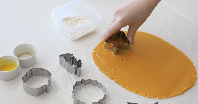 Woman's hands making cookies from raw dough in the form of halloween symbols