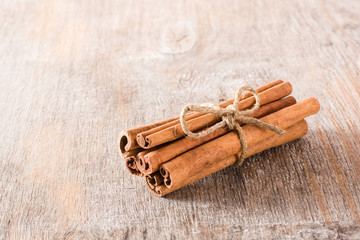 Cinnamon sticks, tied with a rope, lie on a wooden table. Fresh spice