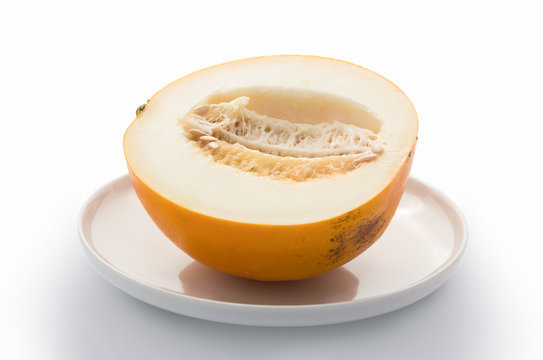 Half of yellow melon on white plate