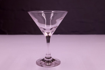 One empty Martini glass with a pink background .