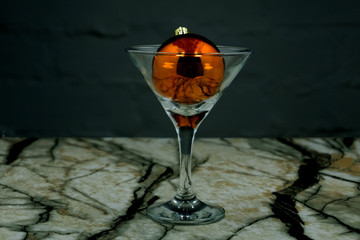 festive Christmas glass transparent ball in a Martini glass marble background