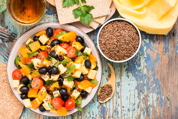 Greek salad and flax seeds on a wooden table. Top view