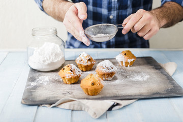 Man cooking homemade cupcakes with raisins and powdered sugar
