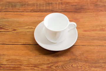 Empty white cup with handle on white saucer
