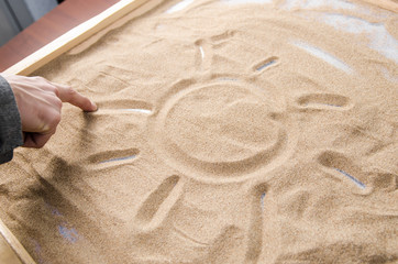 a man draws by his  finger on the sand symbol of the sun