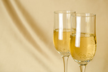 two glasses of champagne on a background of a fabric of golden color