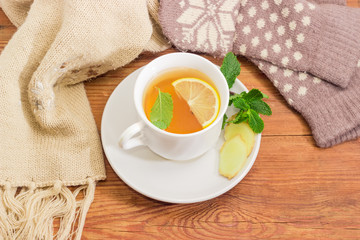Tea with lemon, mint, ginger against of woolen mittens, scarf