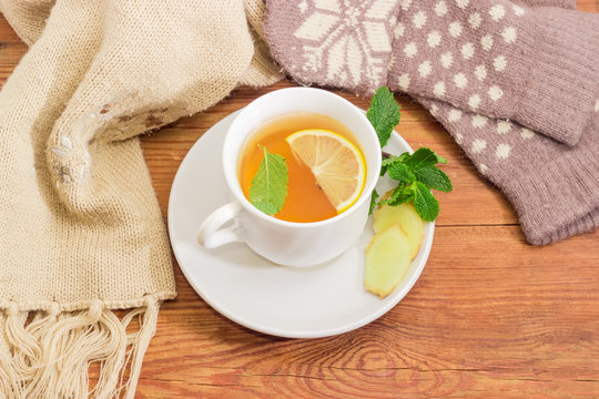 Tea with lemon, mint, ginger against of woolen mittens, scarf