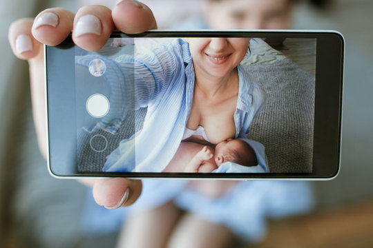 mother breastfeeding mobile photo newborn baby concept. family memories selfie.