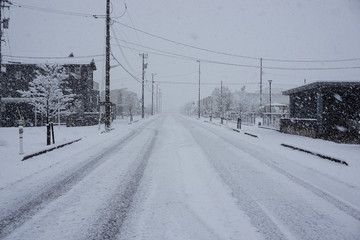 吹雪の中の日本の町と広い道　冬素材　北陸富山県