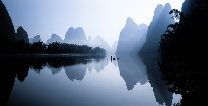 Person on rowboat in Li River at sunrise, China