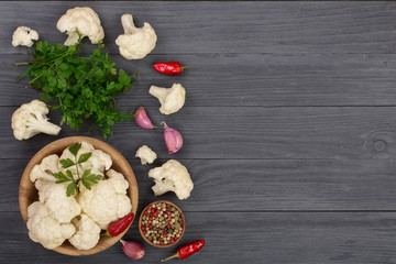 Fresh cauliflower with garlic and chili peppers on black wooden background with copy space for your text. Top view