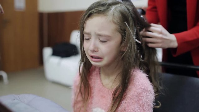 Little girl crying until the hairdresser combs her hair