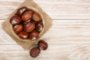 chestnut in bowl on white wooden background with copy space for your text. Top view. Flat lay